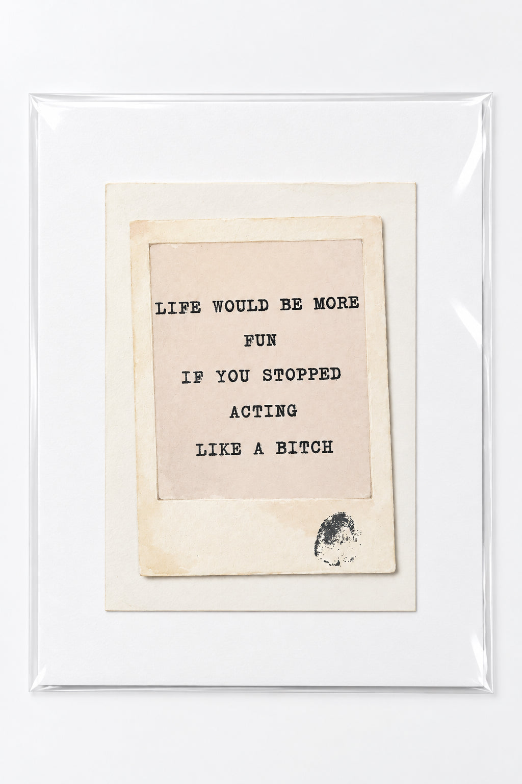 A framed typographic art print with a white mat and clear protective plastic, placed on a wooden surface. The print features a beige central card with black text reading, 'LIFE WOULD BE MORE FUN IF YOU STOPPED ACTING LIKE A BITCH.