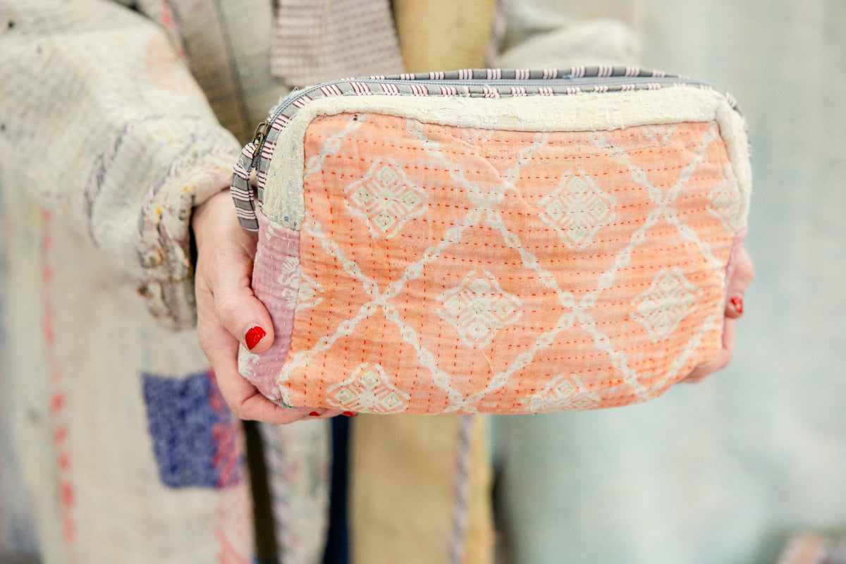 Rahabs Rope Sunburst Threads Antique Kantha cosmetic bag with peach diamond pattern held in hands