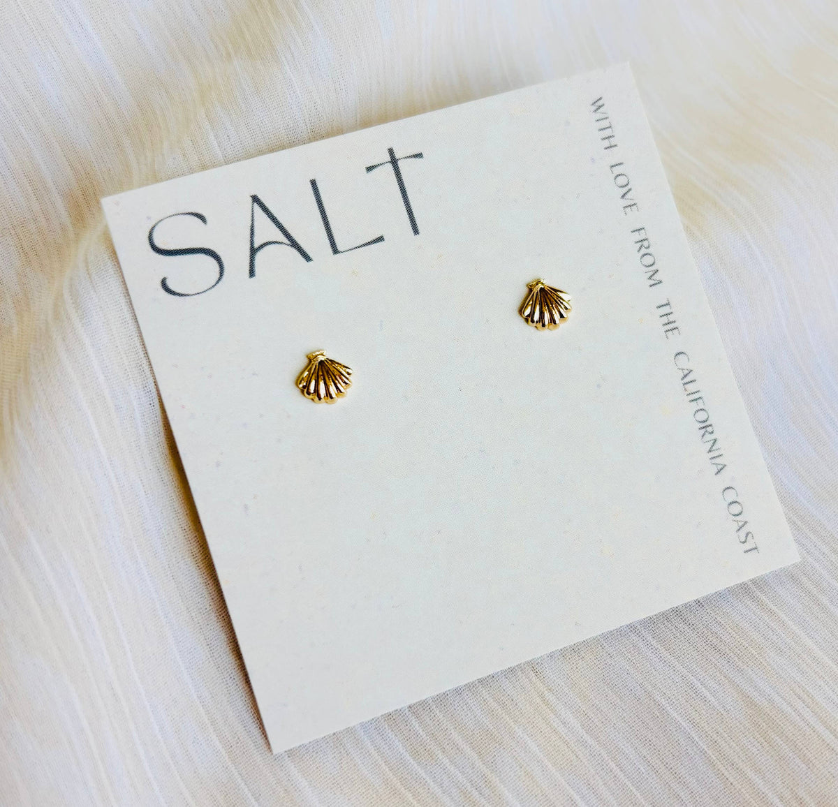 Gold seashell stud earrings by SALT by Sarah Curtis on branded display card