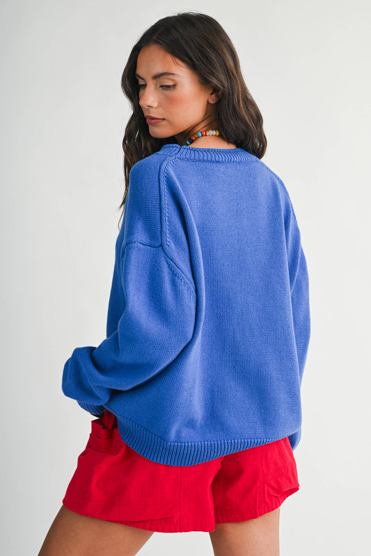 Woman wearing a blue sweater and red shorts on a plain background