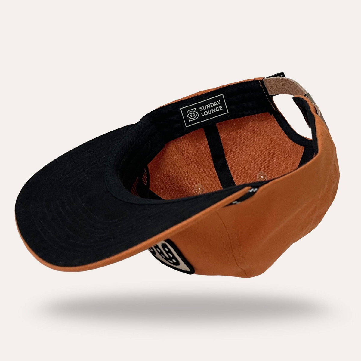 Interior view of Sunday Lounge Snake Hat in desert orange showing black brim and branded label