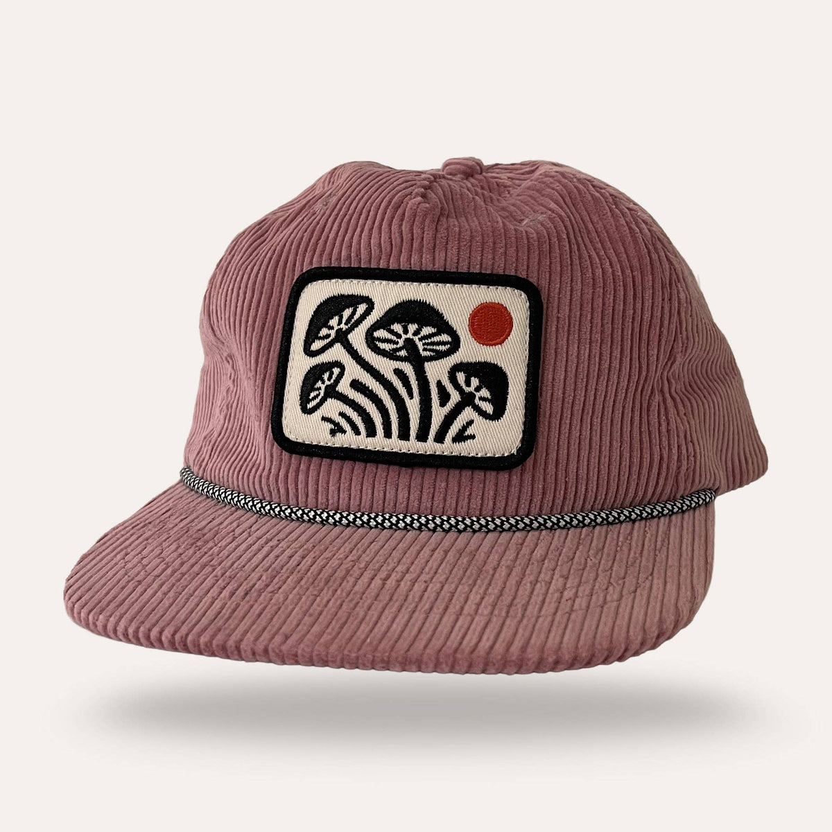 Sunday Lounge pink corduroy mushroom hat with a rectangular patch featuring black mushrooms and a red sun