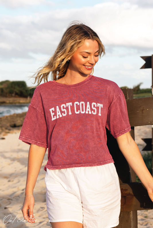 Woman wearing a 'East Coast' t-shirt on a beach