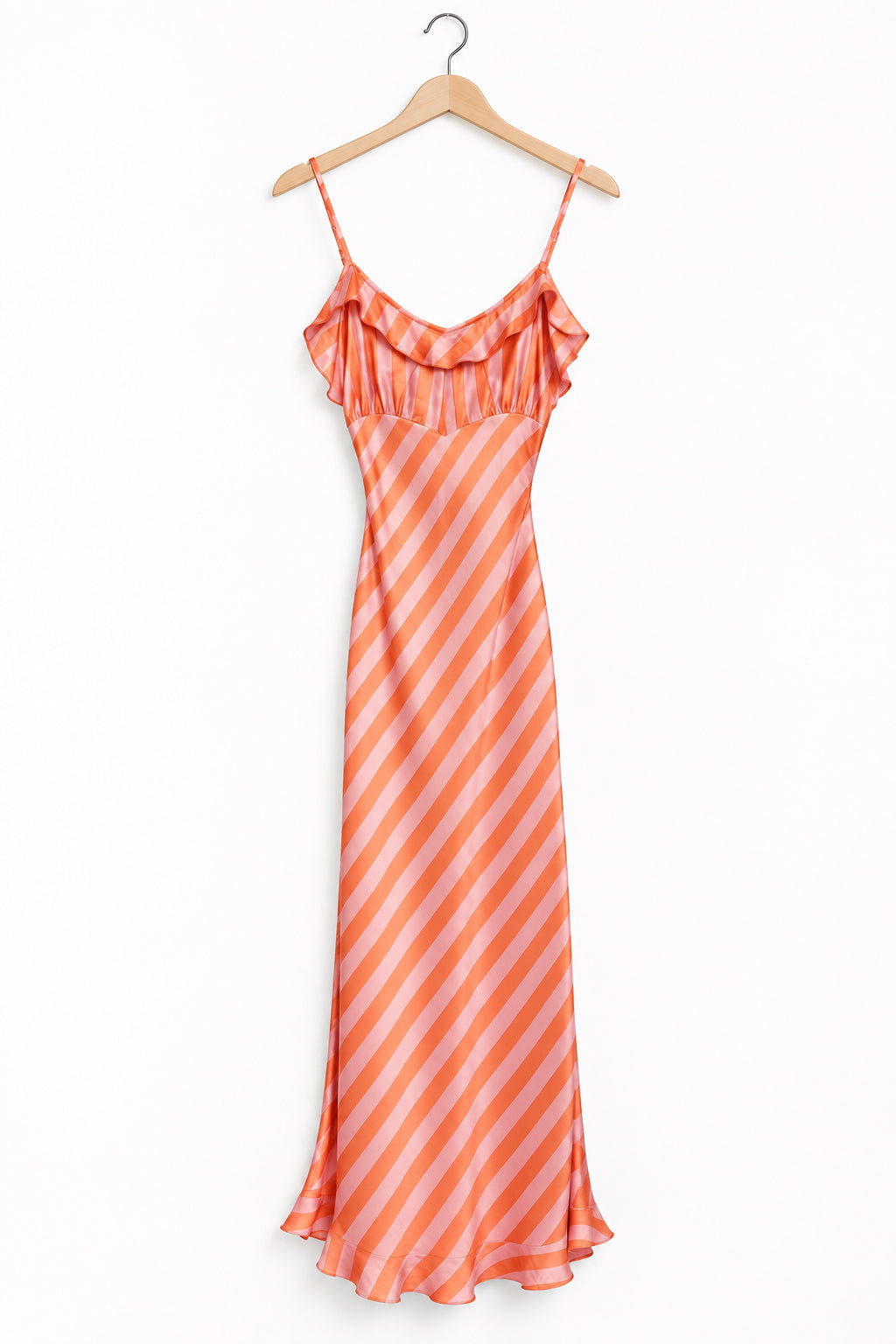 An orange and white striped spaghetti-strap maxi dress hanging on a wooden hanger in front of a dark charcoal door.