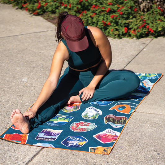 Person in dark green activewear stretching on a Sprints National Parks car seat cover towel