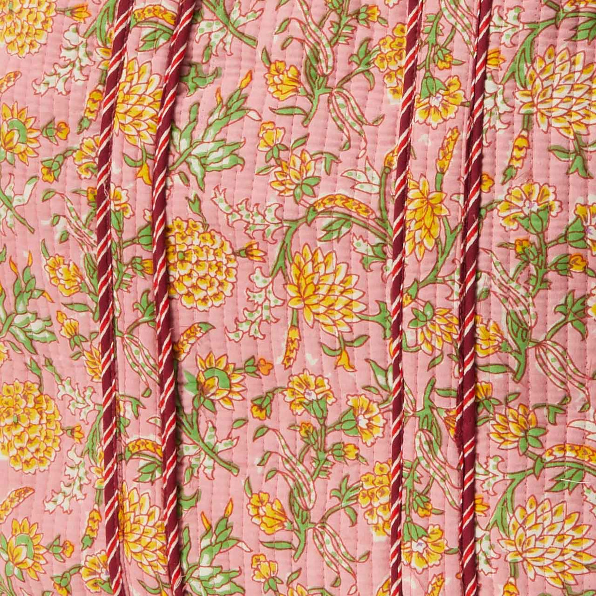 Close up of Marigold Blush quilted tote bag fabric with yellow and green floral print and striped red handles