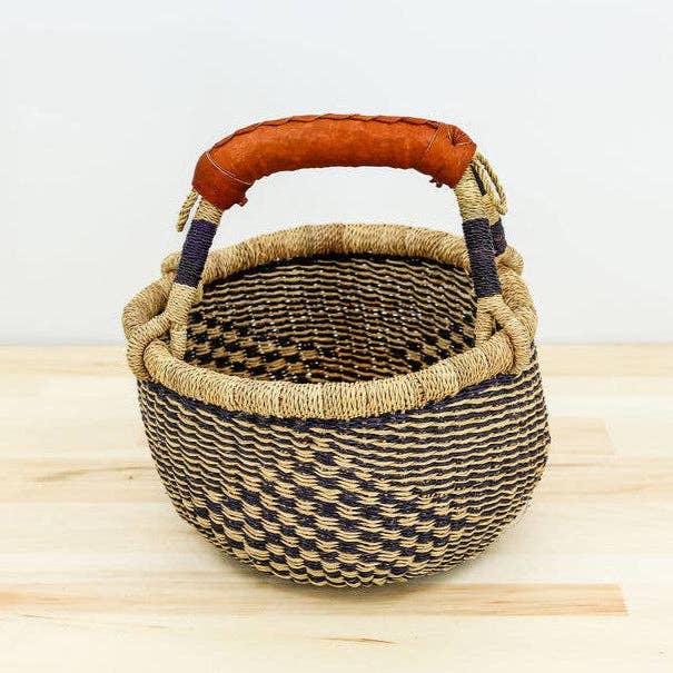 Woven basket with a brown handle on a wooden surface