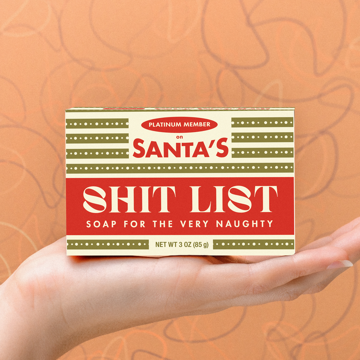 Whiskey River Soap Co Santas Shitlist triple-milled bar soap in a red and green holiday themed box held in a hand