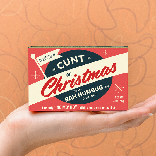 Whiskey River Soap Co Don't Be a Cunt on Christmas triple-milled bar soap in a red and white box held in a hand